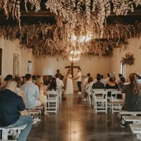 Wedding ceremony in the hall beneath a dried-floral installation