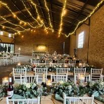The hall set with long tables, greenery and fairy lights for a reception